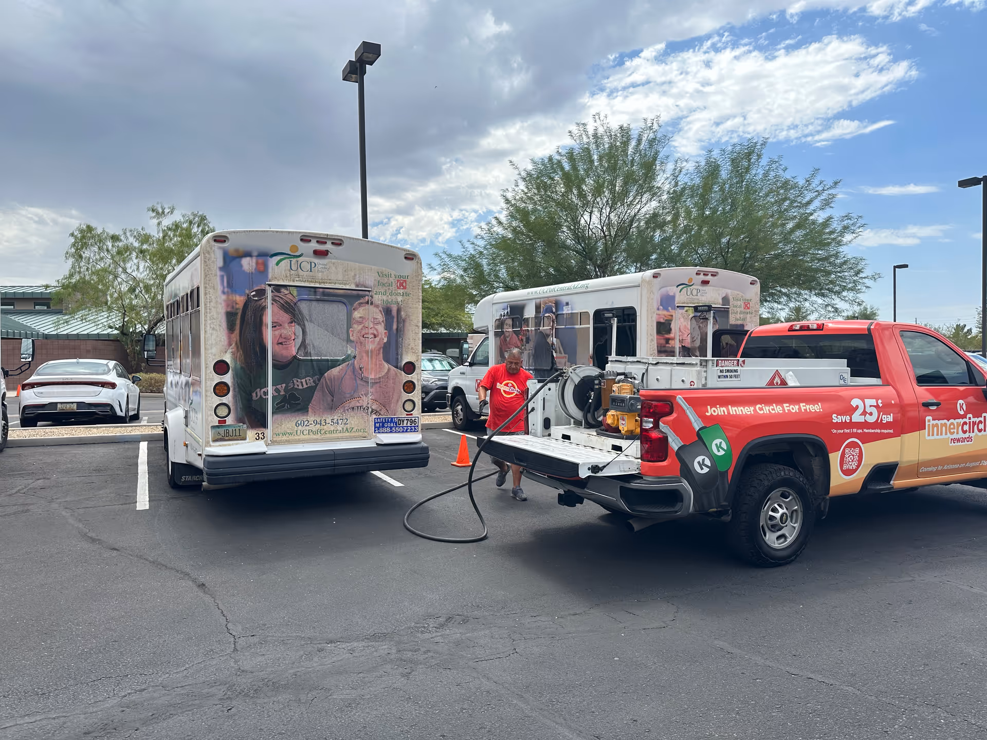 Two UCP of Central Arizona buses in a parking lot with a service truck nearby.