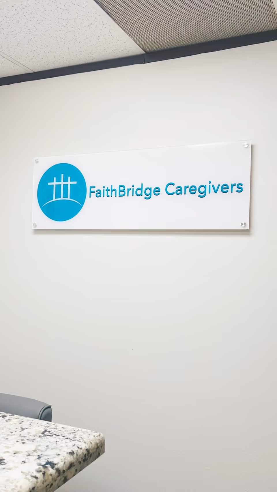 Interior wall sign reads FaithBridge Caregivers with a blue circular logo above a granite counter.