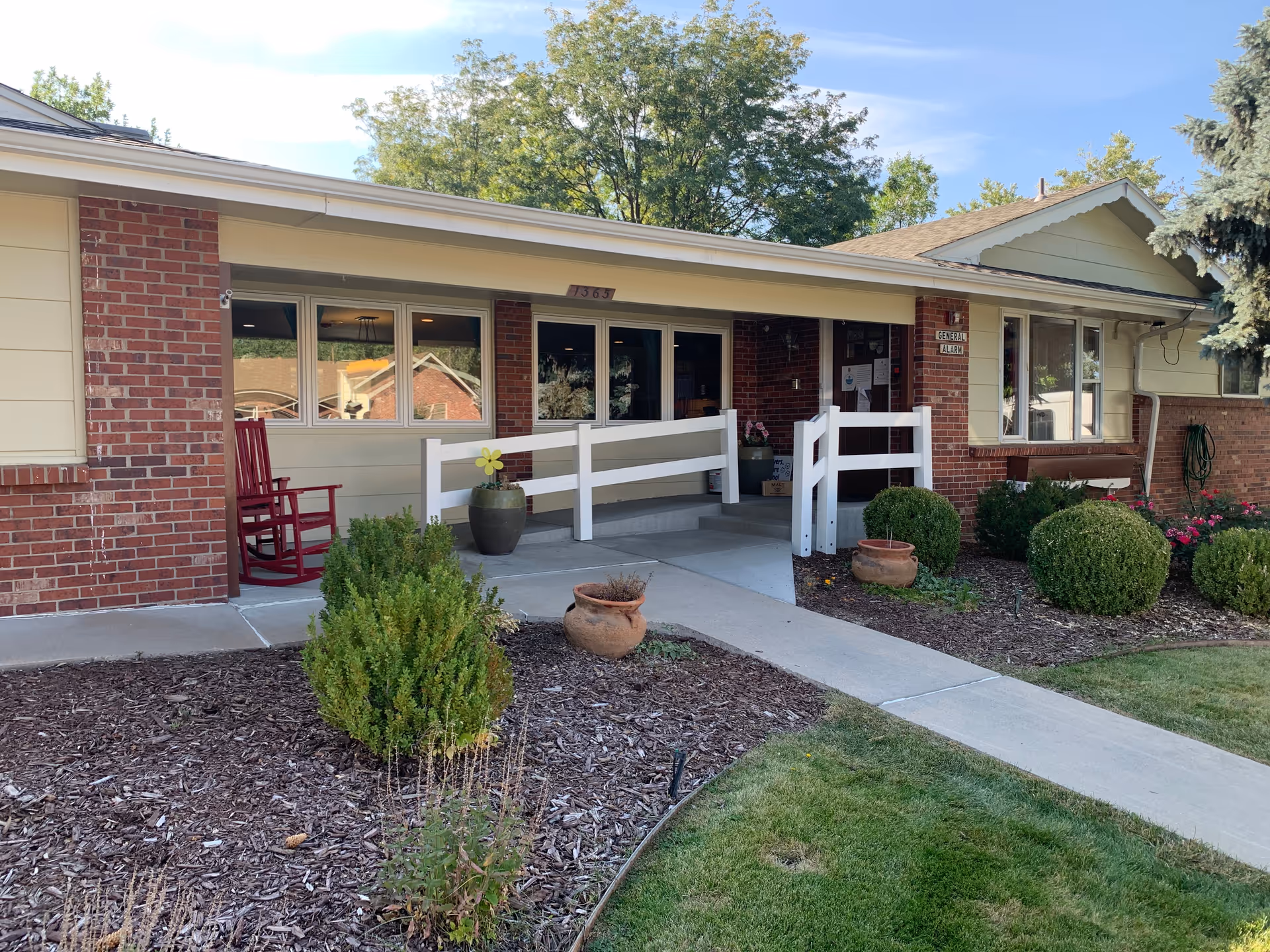 Applewood Our House Assisted Living: single-story building with brick, beige siding, front porch, and landscaping.