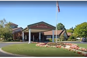 Front exterior view of Woodbrook Assisted Living Residence, with circular driveway and flagpole.