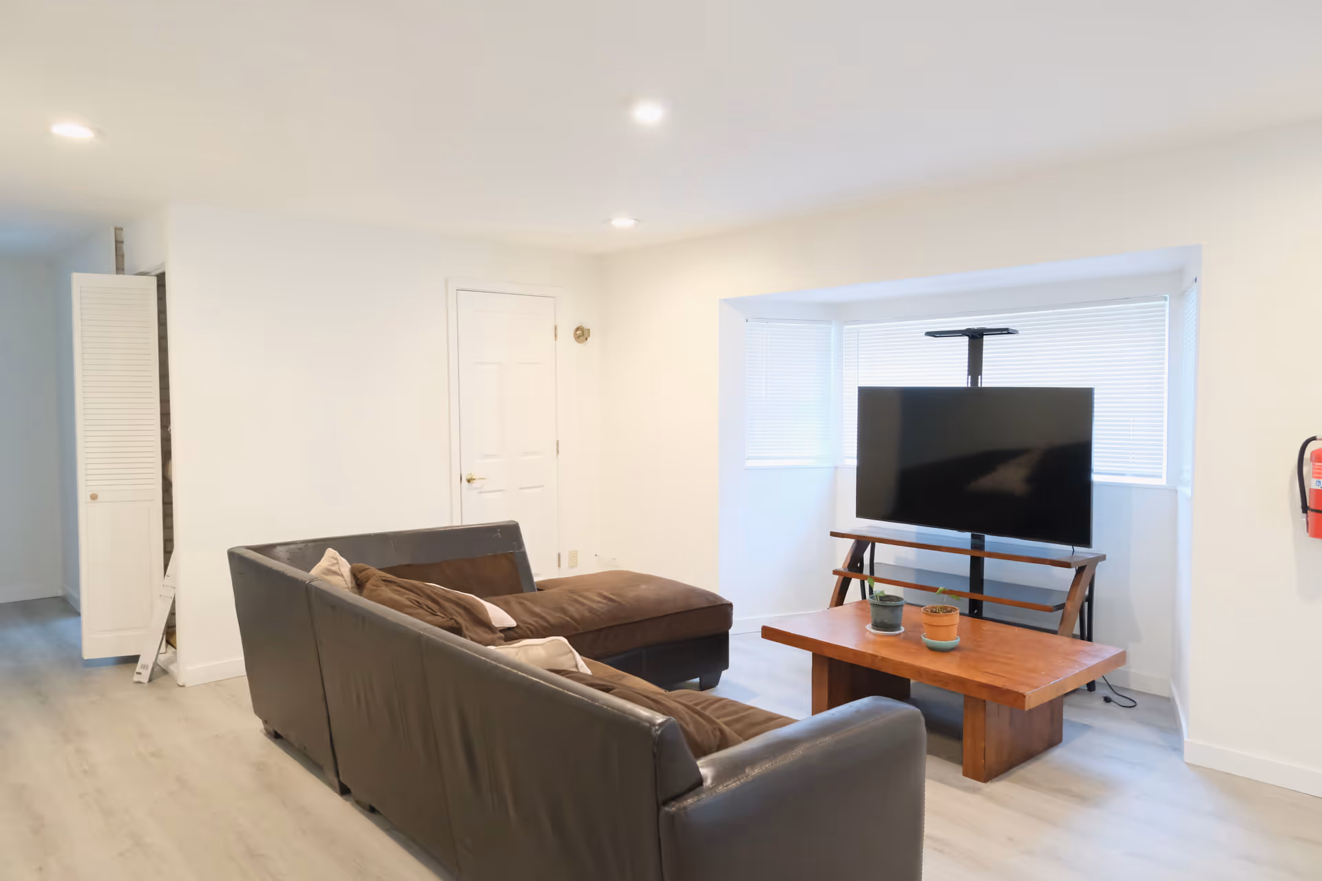 Bright living room with a gray sofa, coffee table, and mounted TV.