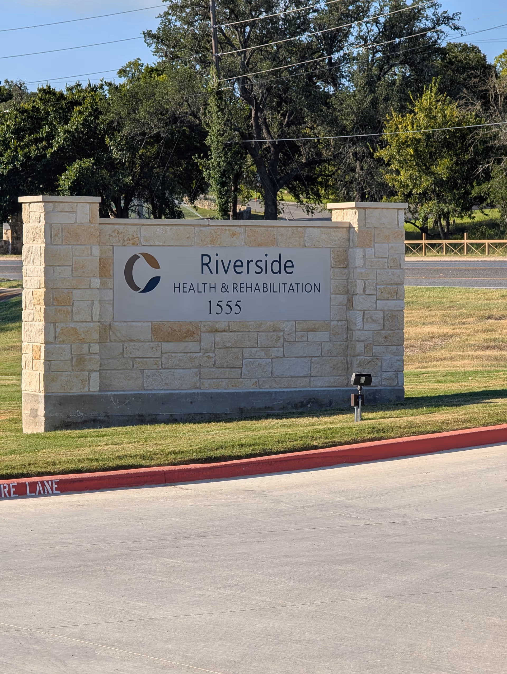 Stone entrance sign for Riverside Health & Rehabilitation along a road.