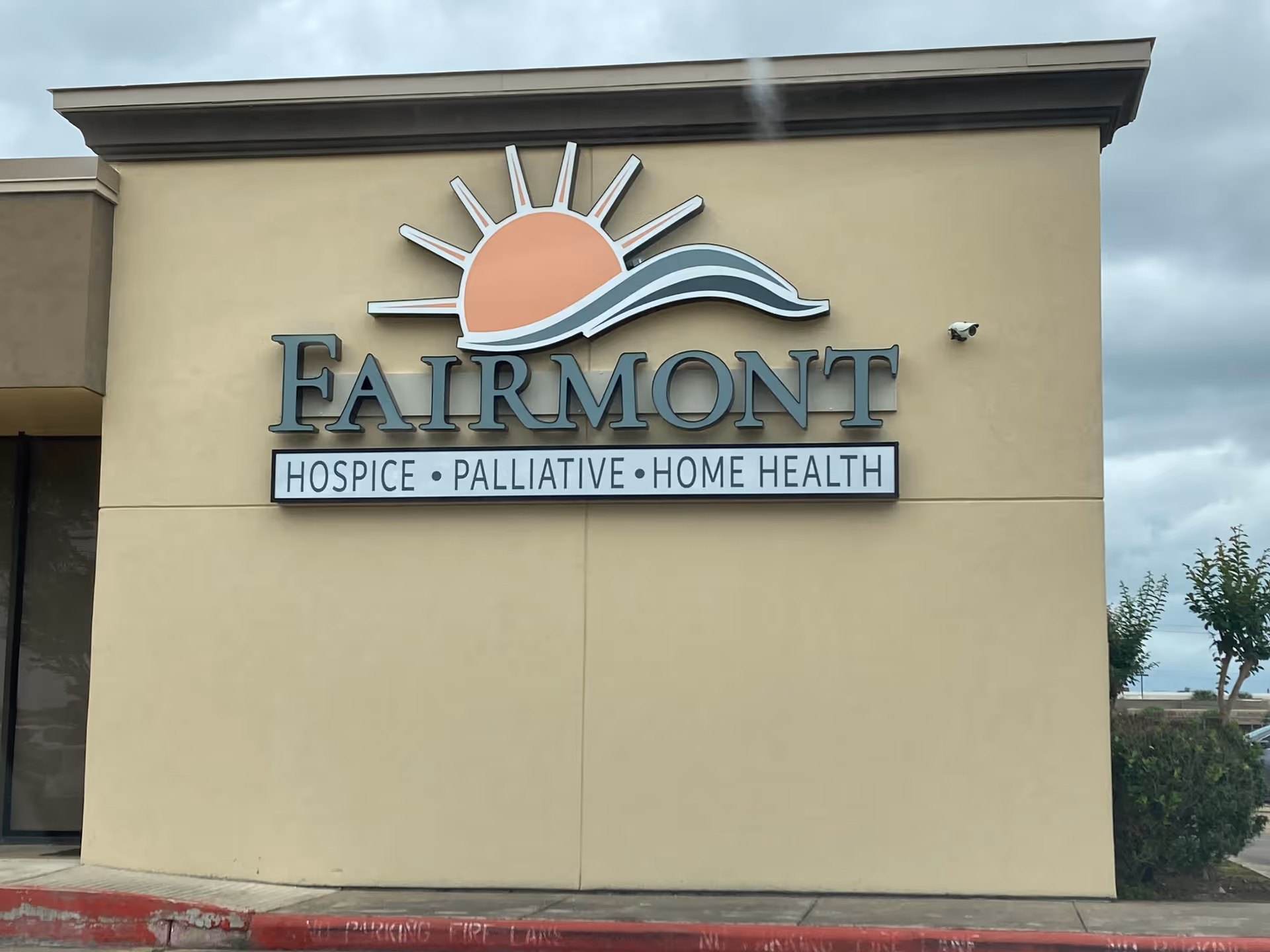 Exterior of Fairmont Hospice building featuring sun emblem sign.