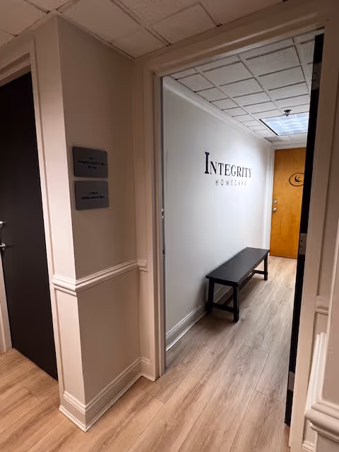 Interior hallway of a senior living facility with a bench and Integrity sign on wall.
