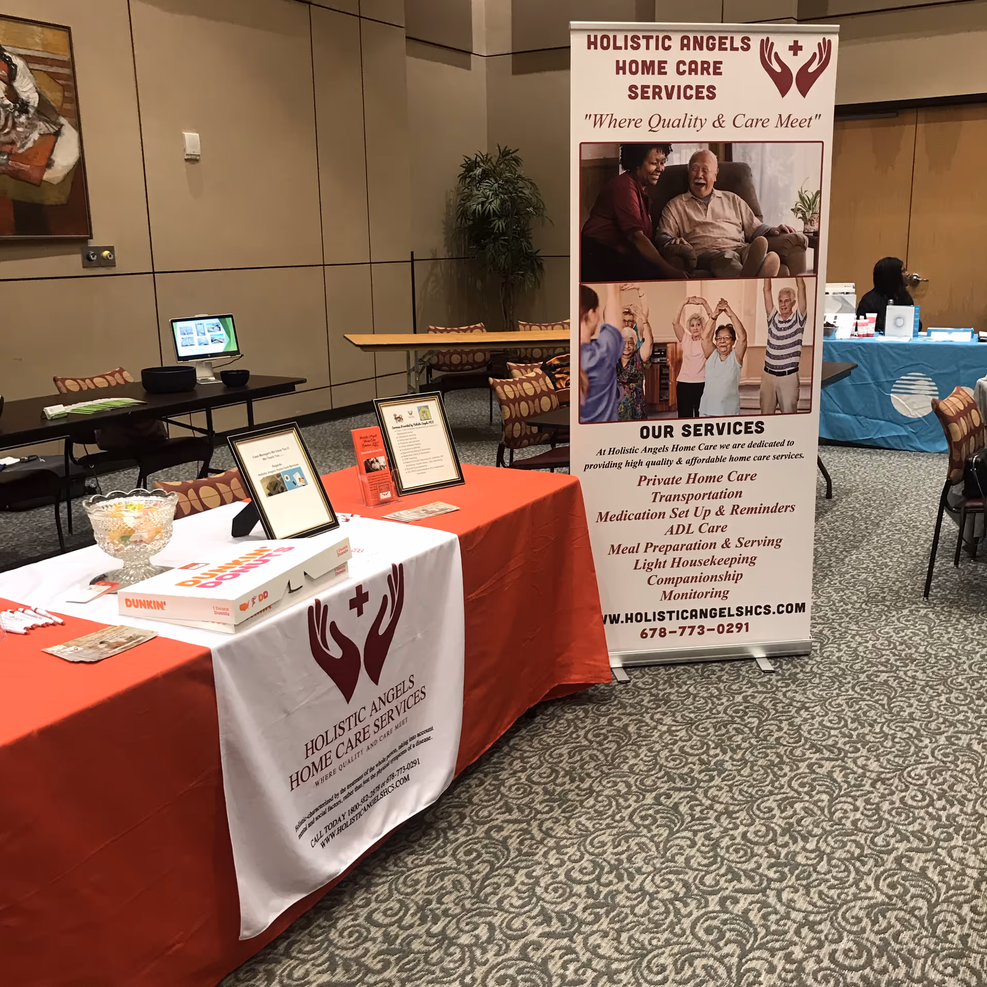 Indoor expo booth for Holistic Angels Home Care Services with banner and tables.