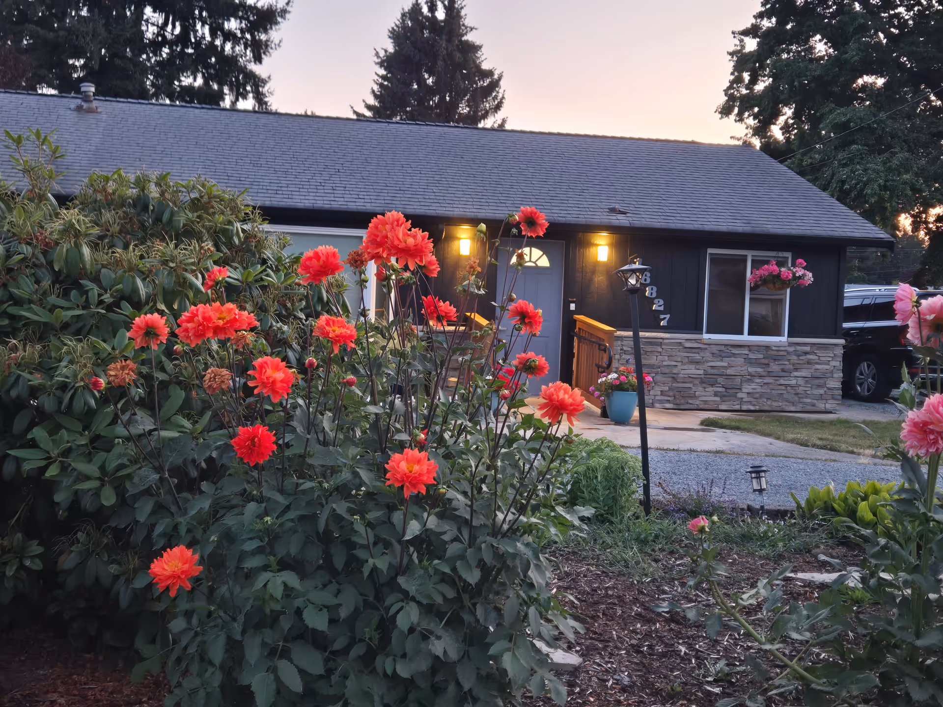 Exterior view of a single-story building with vibrant red flowers in the foreground.