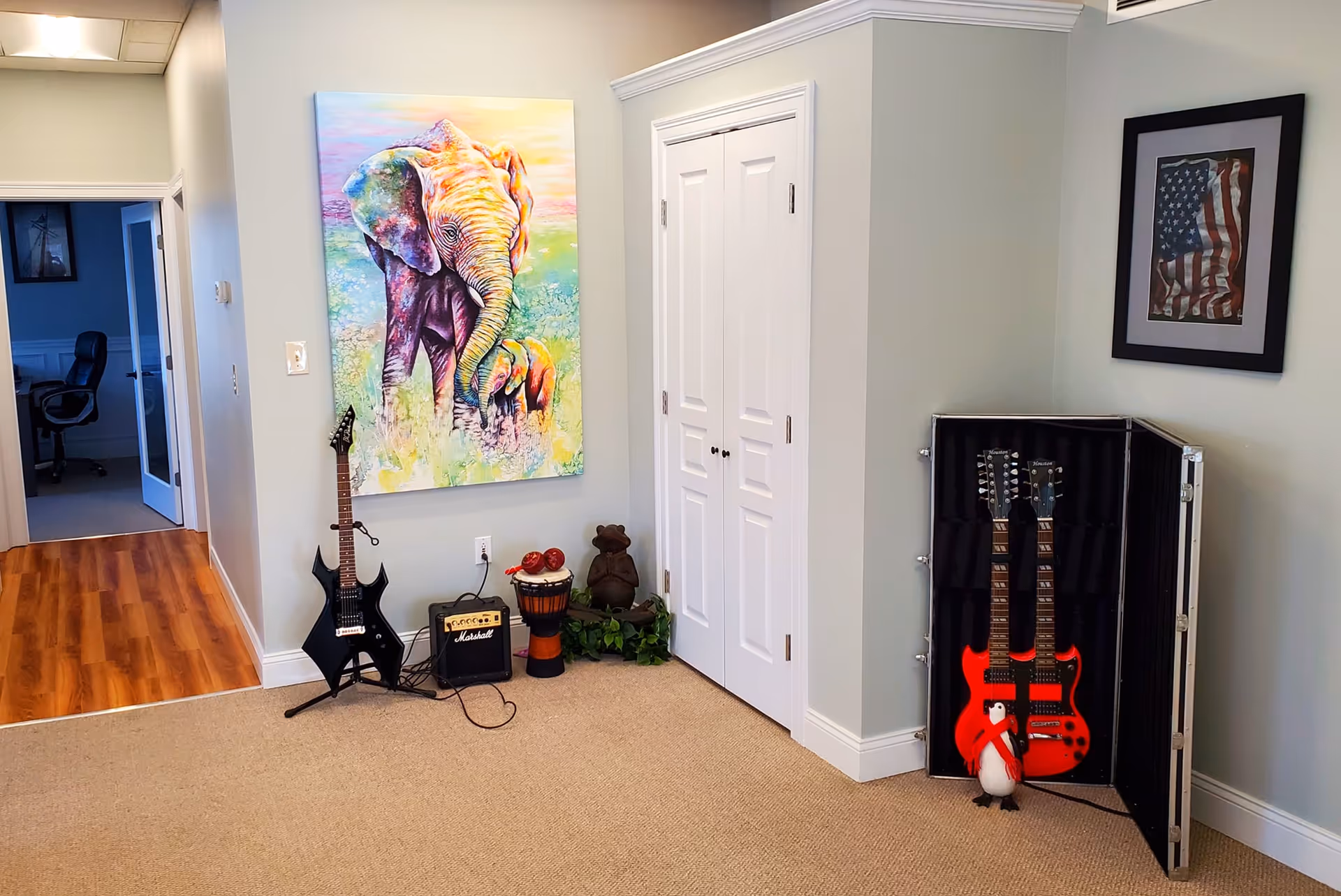 Hallway music corner with guitars, amplifier, elephant artwork, and a framed American flag.