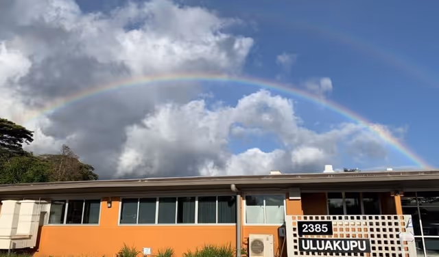 Exterior view of Hawaiʻi State Department of Health facility with a rainbow in the sky.