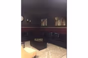 Dark lounge with black leather couches, maroon walls, and patterned tile floor.