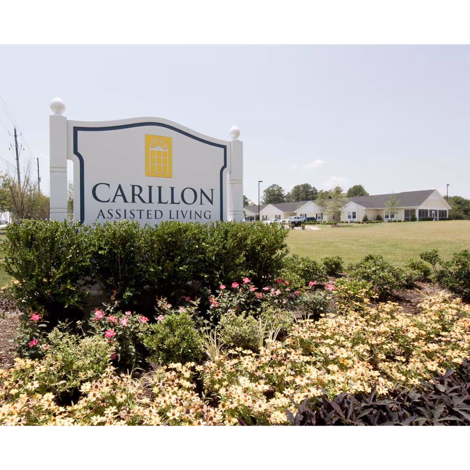 Exterior view of Carillon Assisted Living sign with campus building in background