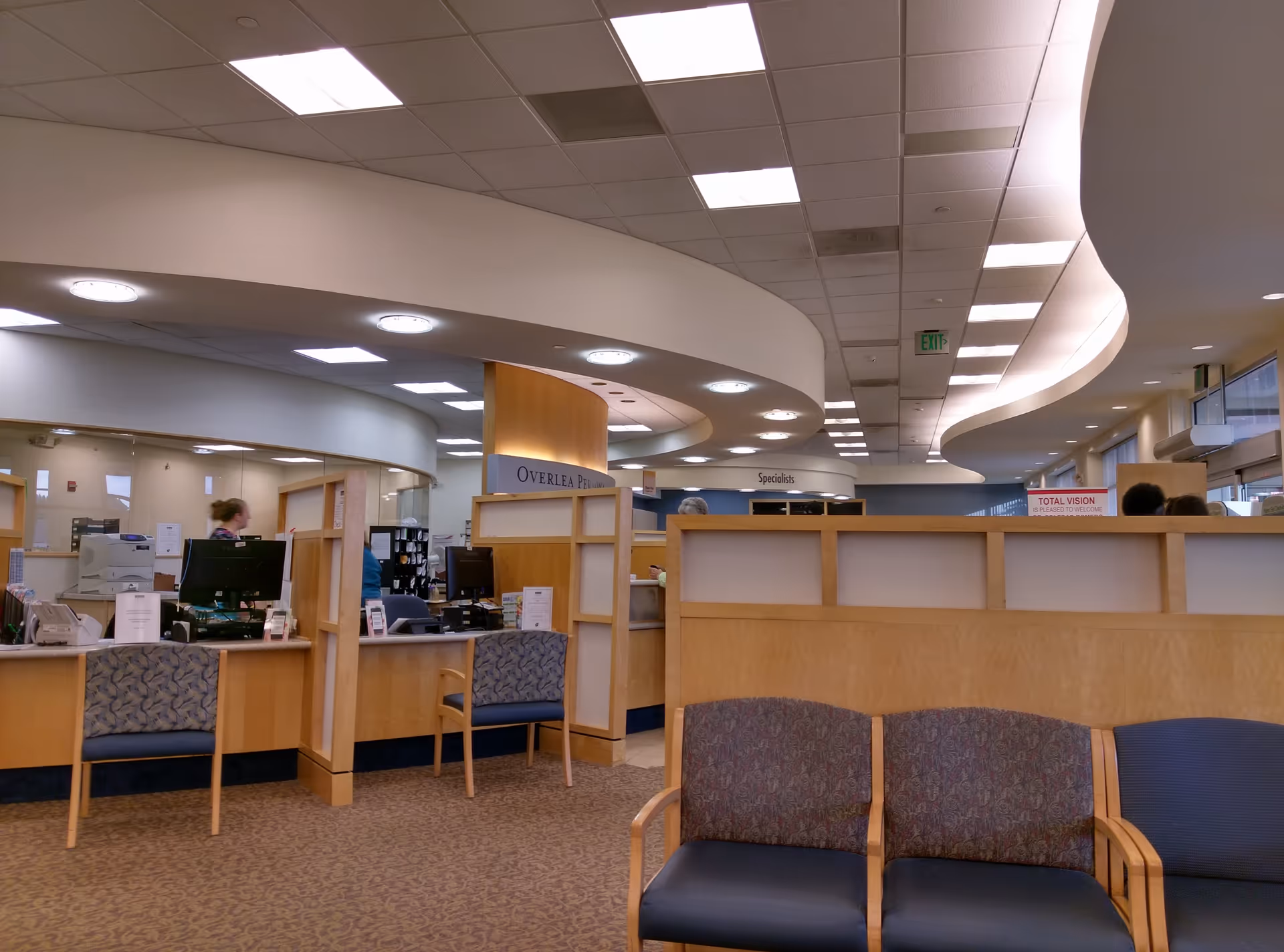 Interior reception area with curved ceiling, desks, computers, and waiting chairs in a medical facility