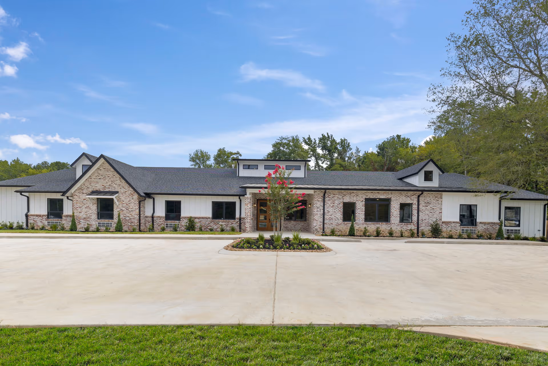 Front view of a single-story brick and siding assisted living facility with landscaping.