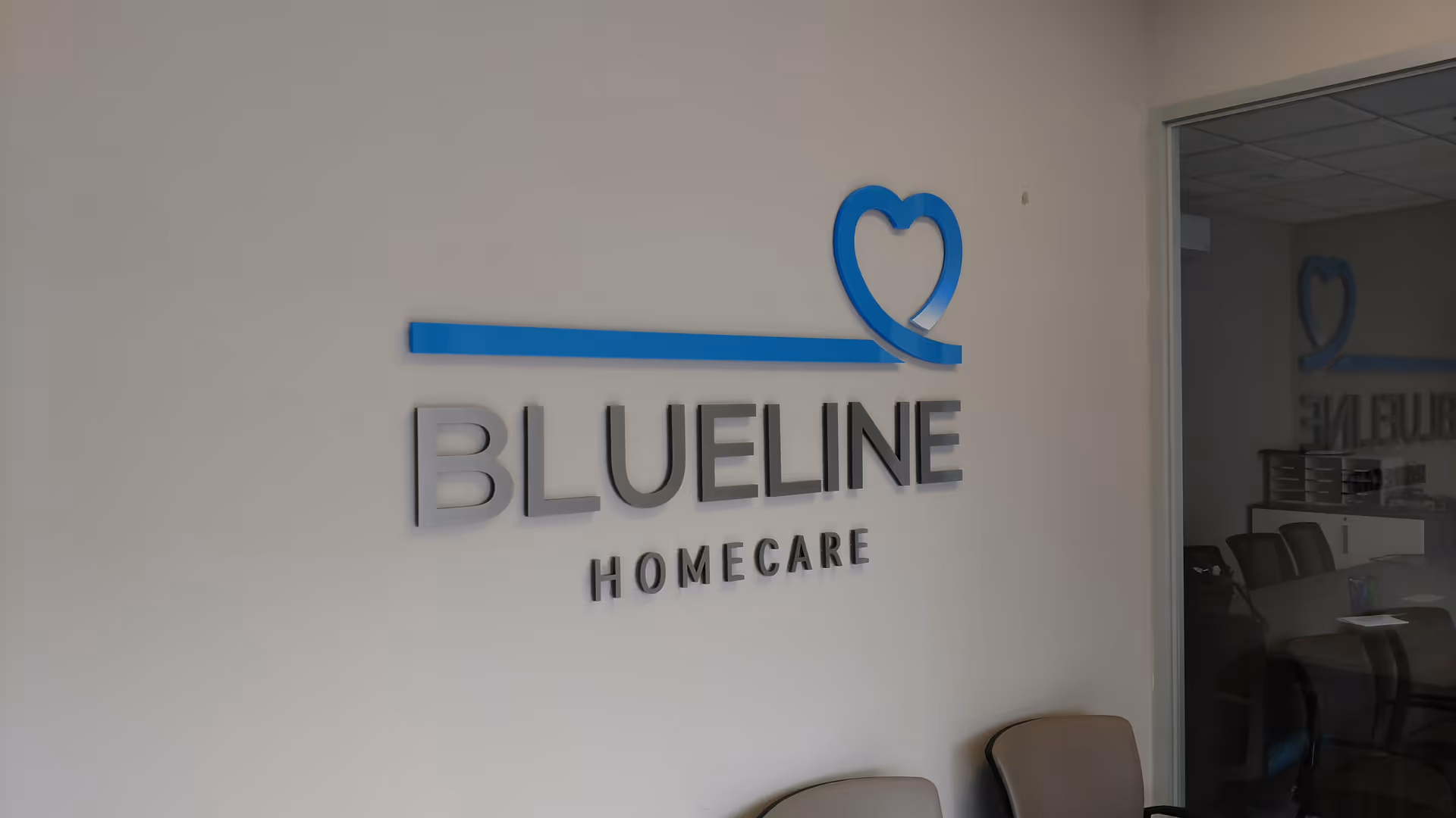 BLUELINE HOMECARE sign with heart logo mounted on a light wall beside seating.