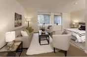 Cozy senior living suite featuring a living area with two chairs, sofa, and a bed.
