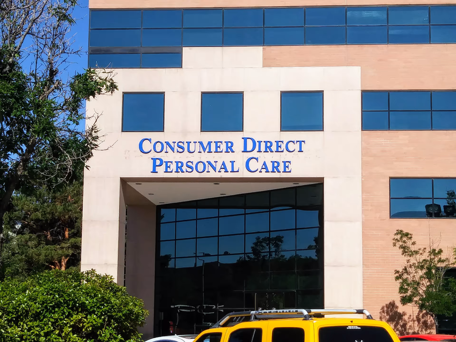 Modern facility exterior with blue-tinted windows and a sign reading Consumer Direct Personal Care.