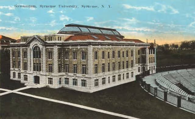 Vintage postcard of a large brick building with curved outdoor seating area.