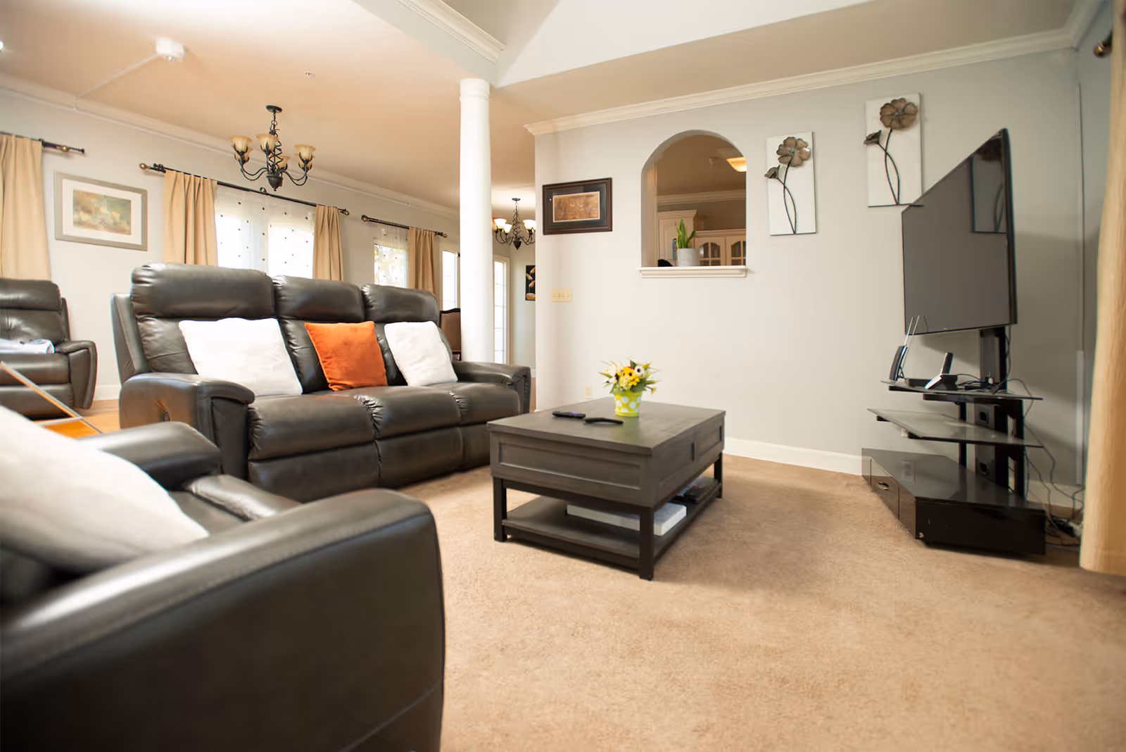 Cozy living room with leather sofas, a coffee table, TV, and arched doorway.