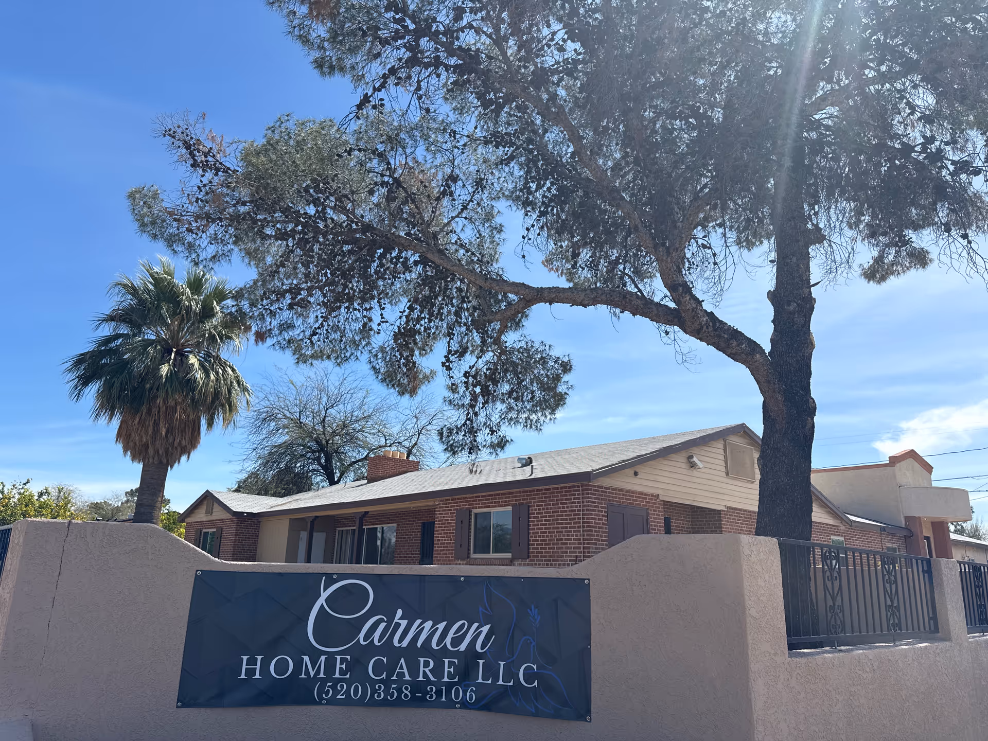 Front exterior view of Carmen Home Care LLC building with sign and trees.