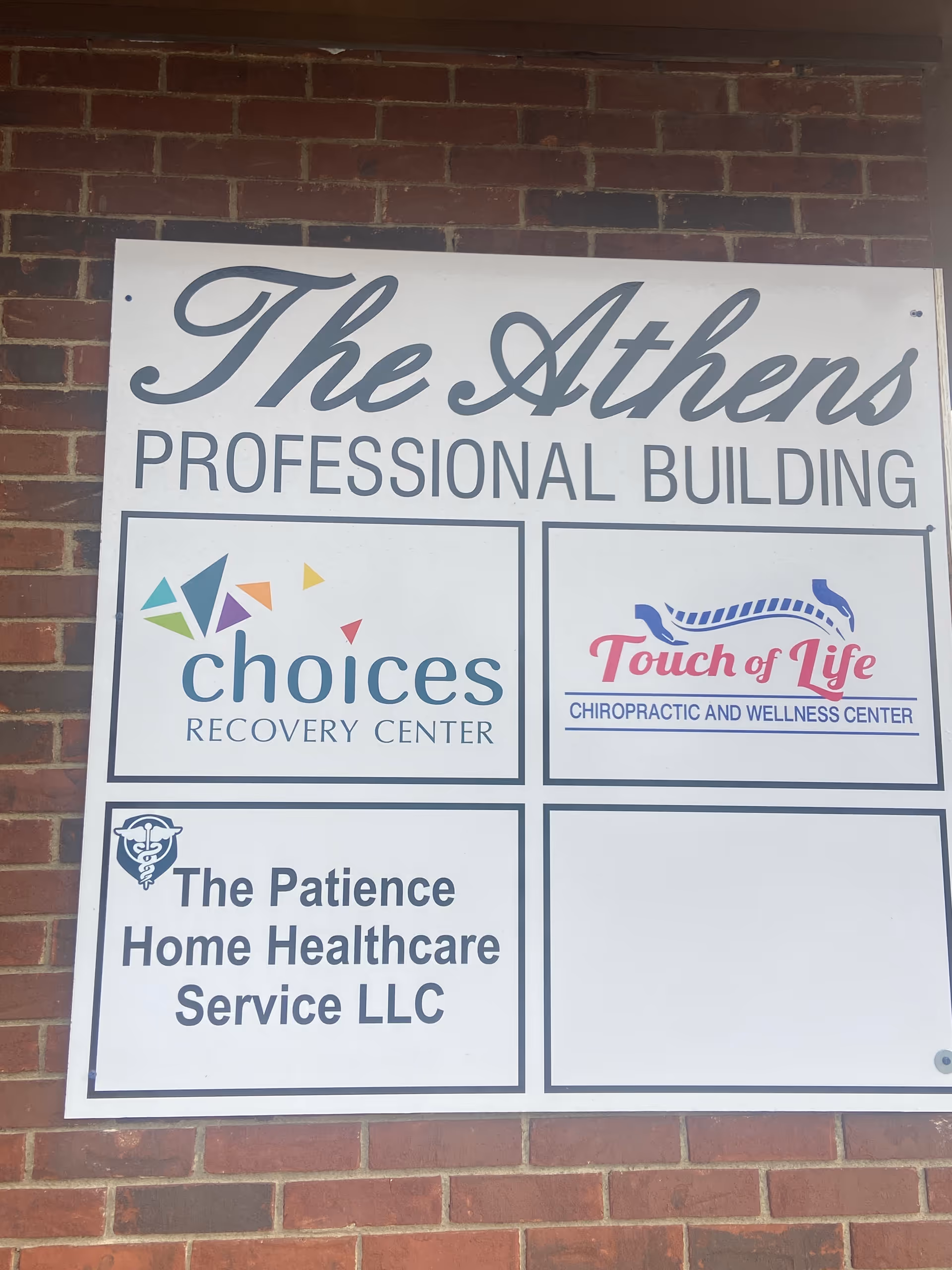 Brick wall sign advertising The Athens Professional Building with multiple tenant logos.