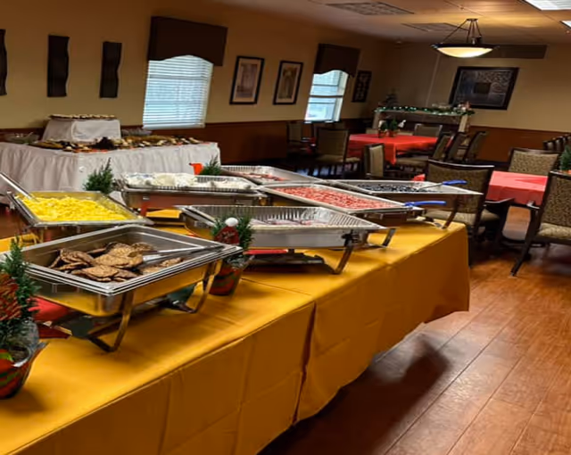 Buffet table with chafing dishes and seating area in a dining room.