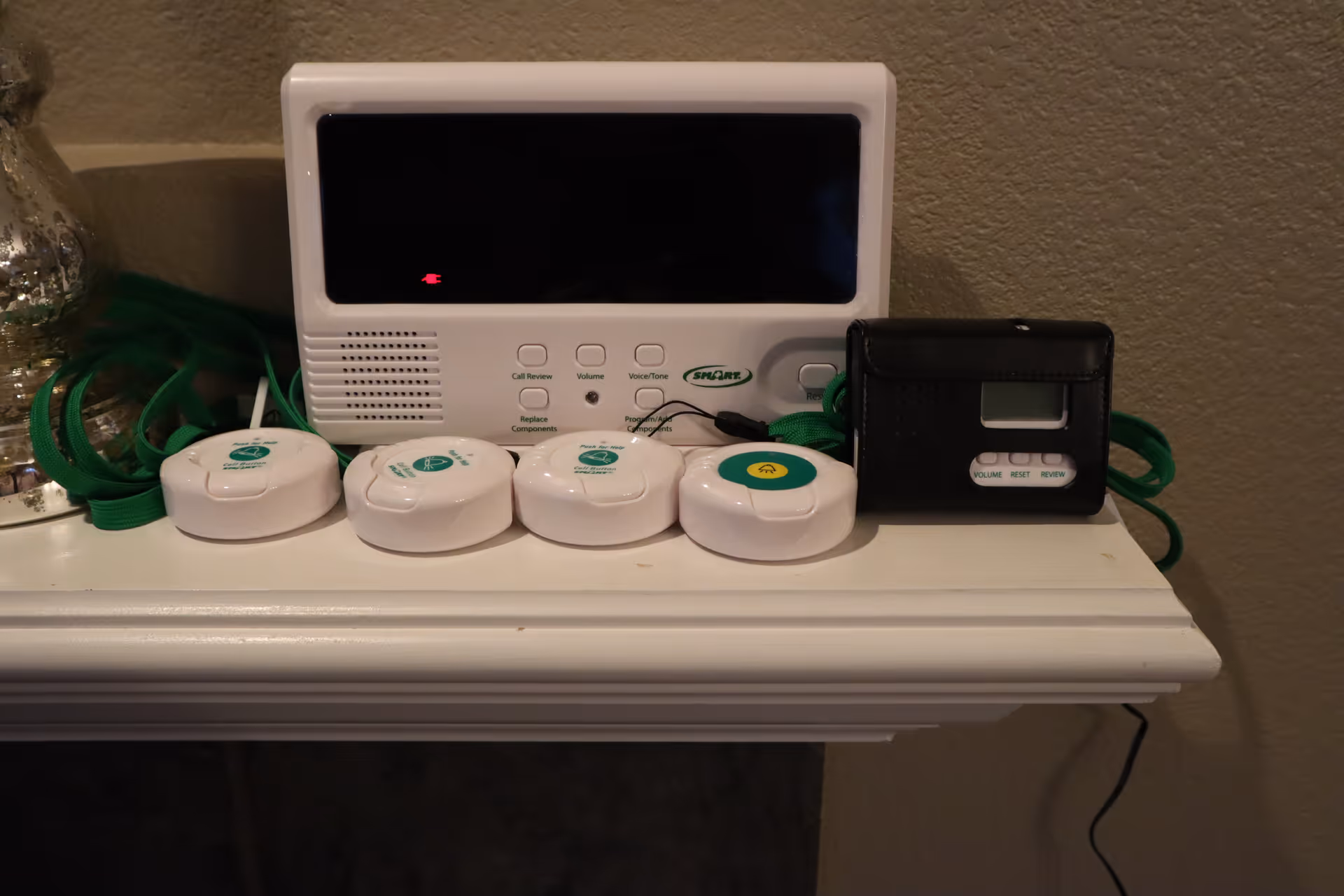 Close-up of a medical alert system and pendant devices on a shelf.