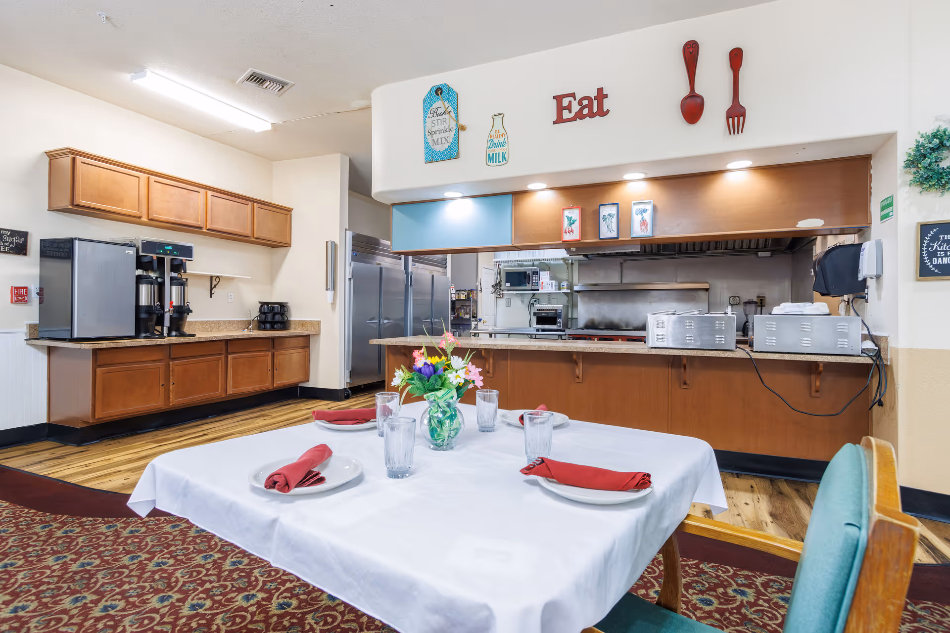 A dining area in a senior living facility with a table set near a kitchen counter.