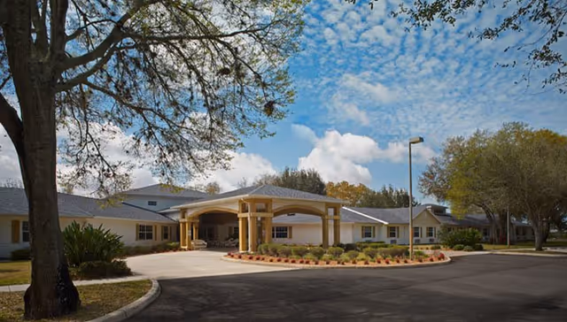 Exterior view of Heron East entrance with a circular driveway and landscaping.