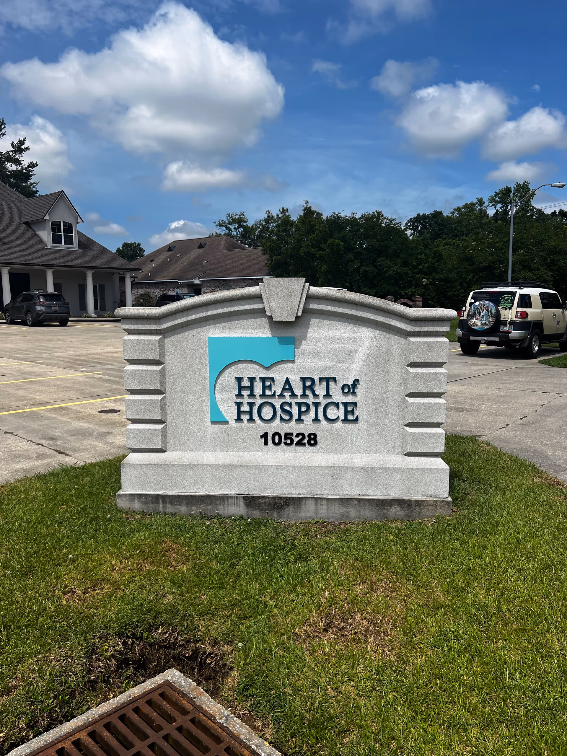 Stone Heart of Hospice sign with logo and address in a parking lot.