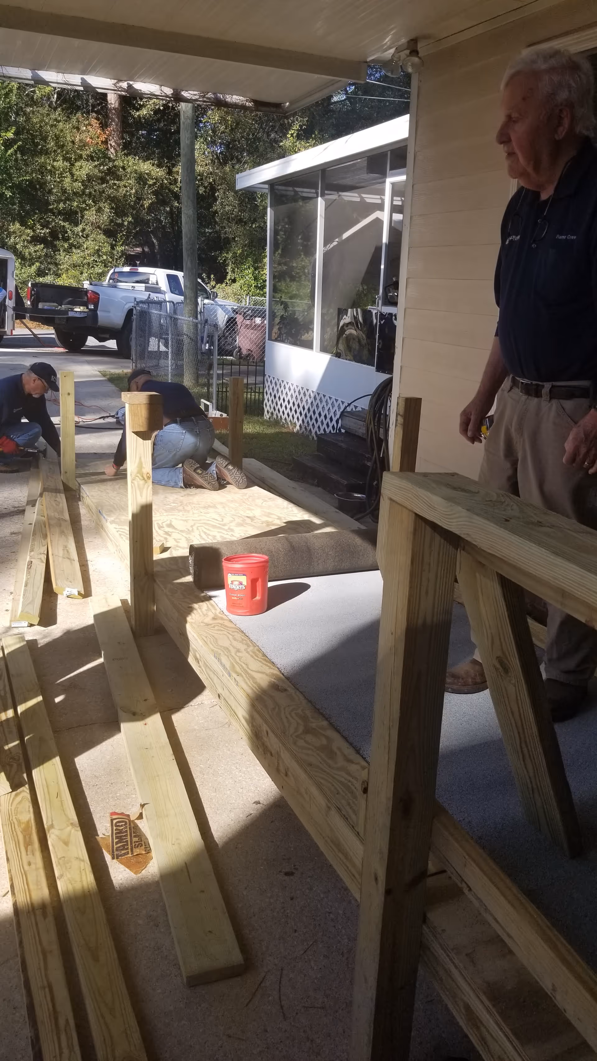 Outdoor construction scene beside a senior home with workers and lumber.
