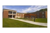 Two-story brick senior living facility with a covered entrance and neatly mowed lawn.