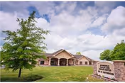 Single-story Springdale health facility with a grassy lawn, trees, and a front sign.