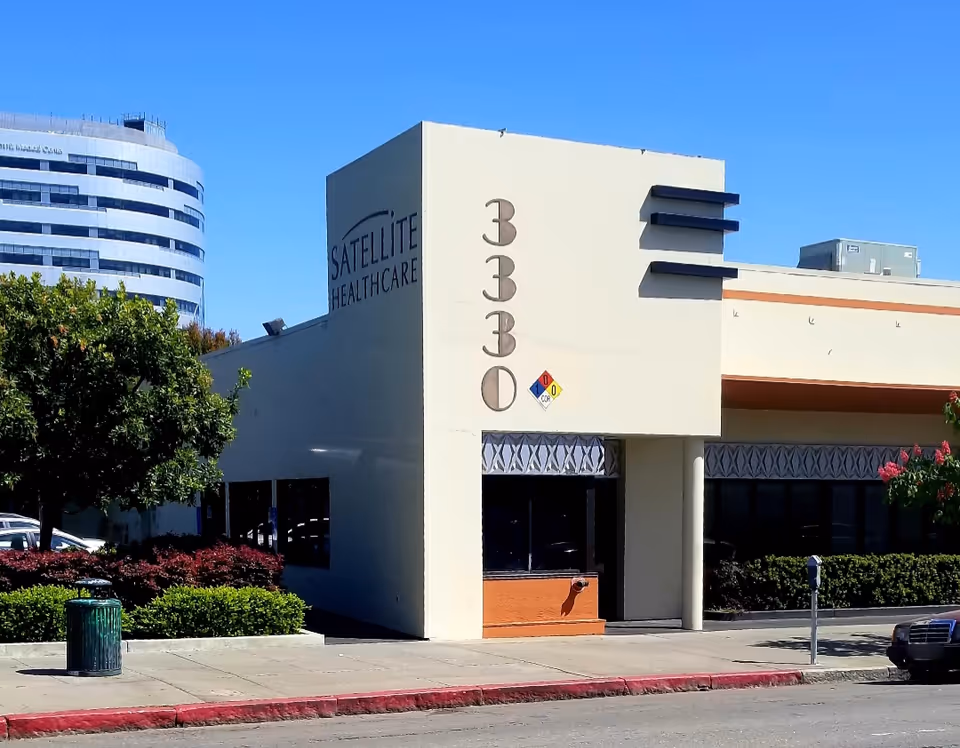 Exterior view of Satellite Healthcare building with street, trees, and sidewalk.