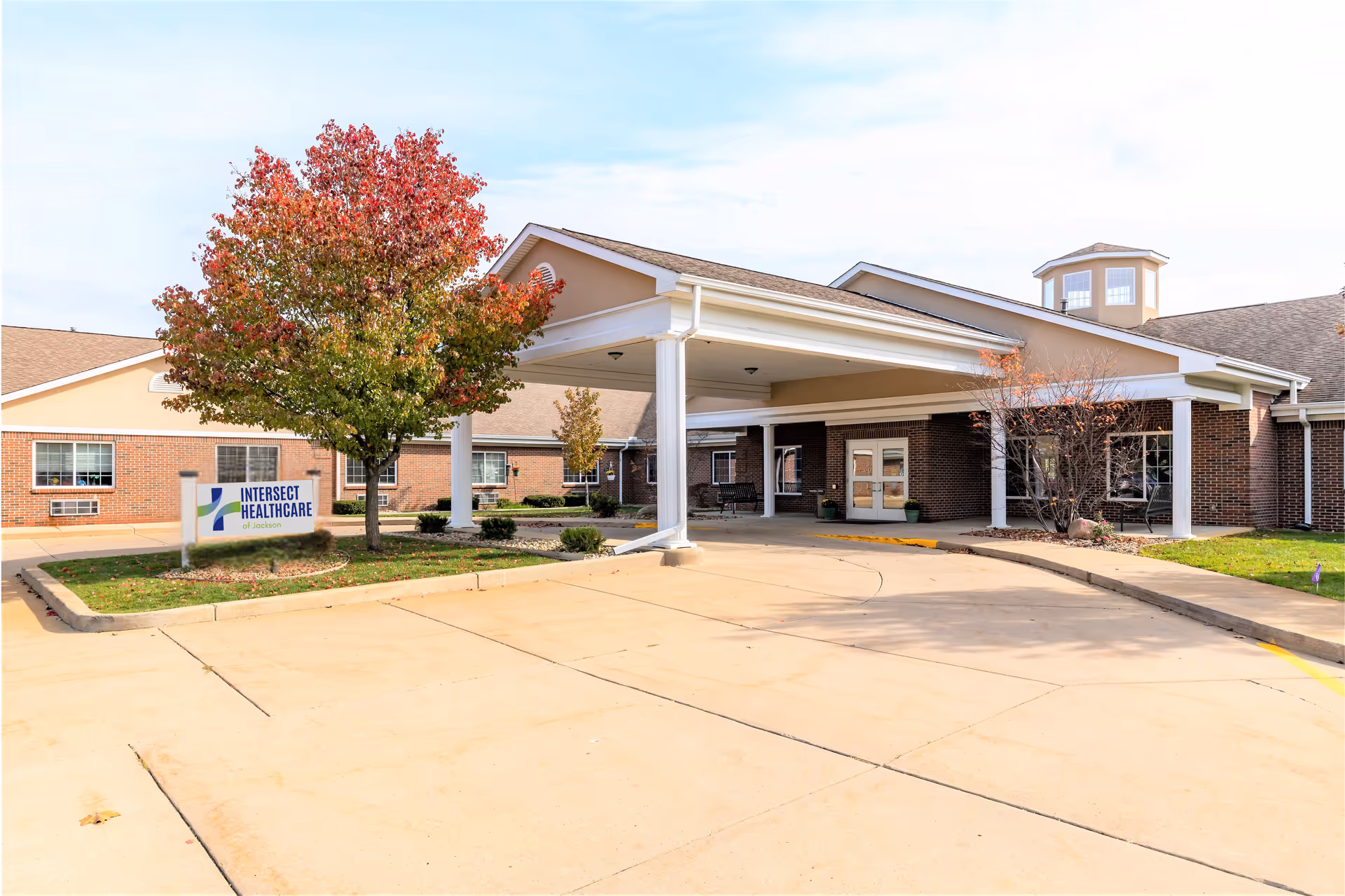 Exterior view of a senior living facility entrance with a covered driveway and landscaping.