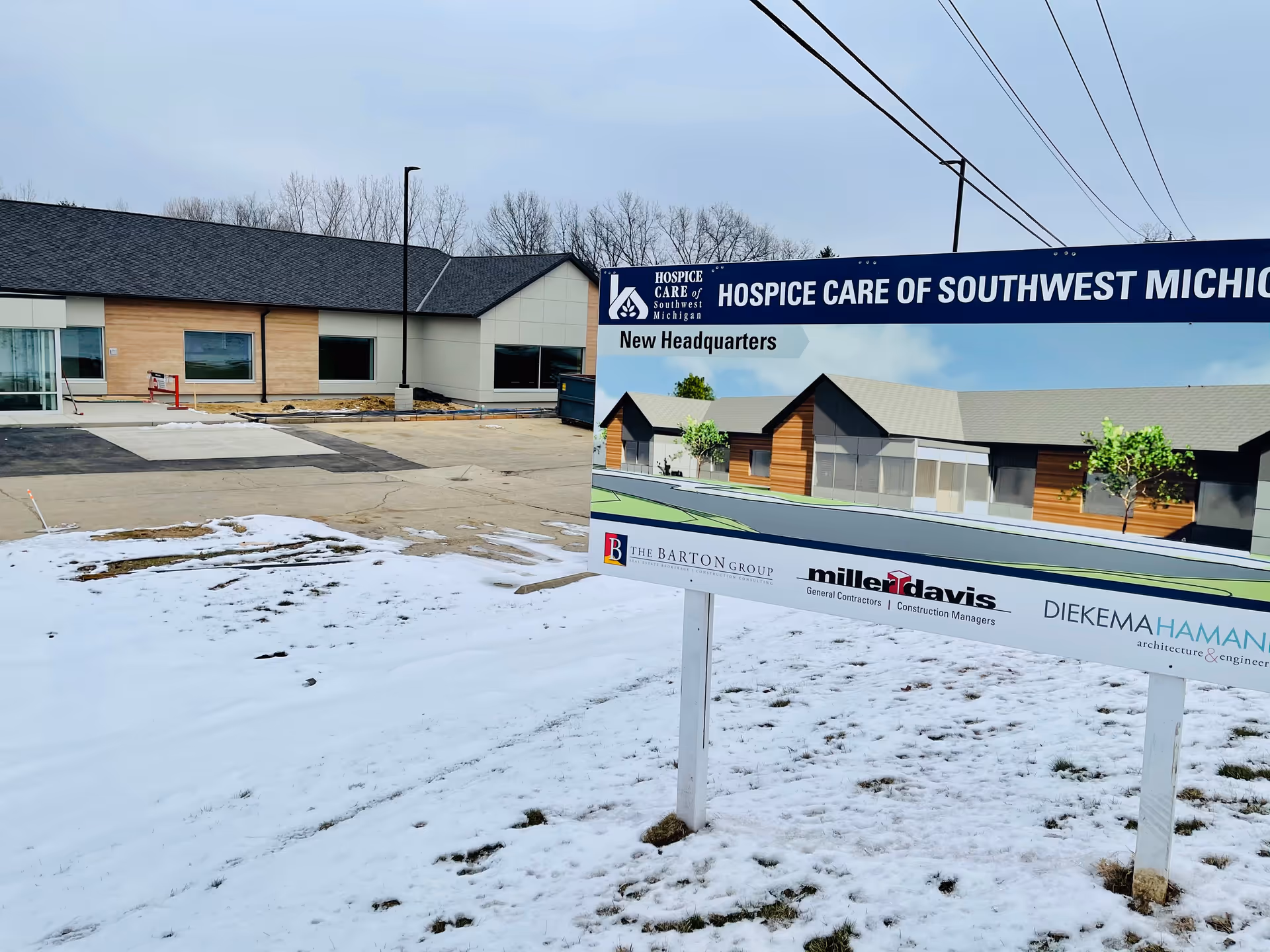 Exterior view of a hospice facility sign and new headquarters construction site.