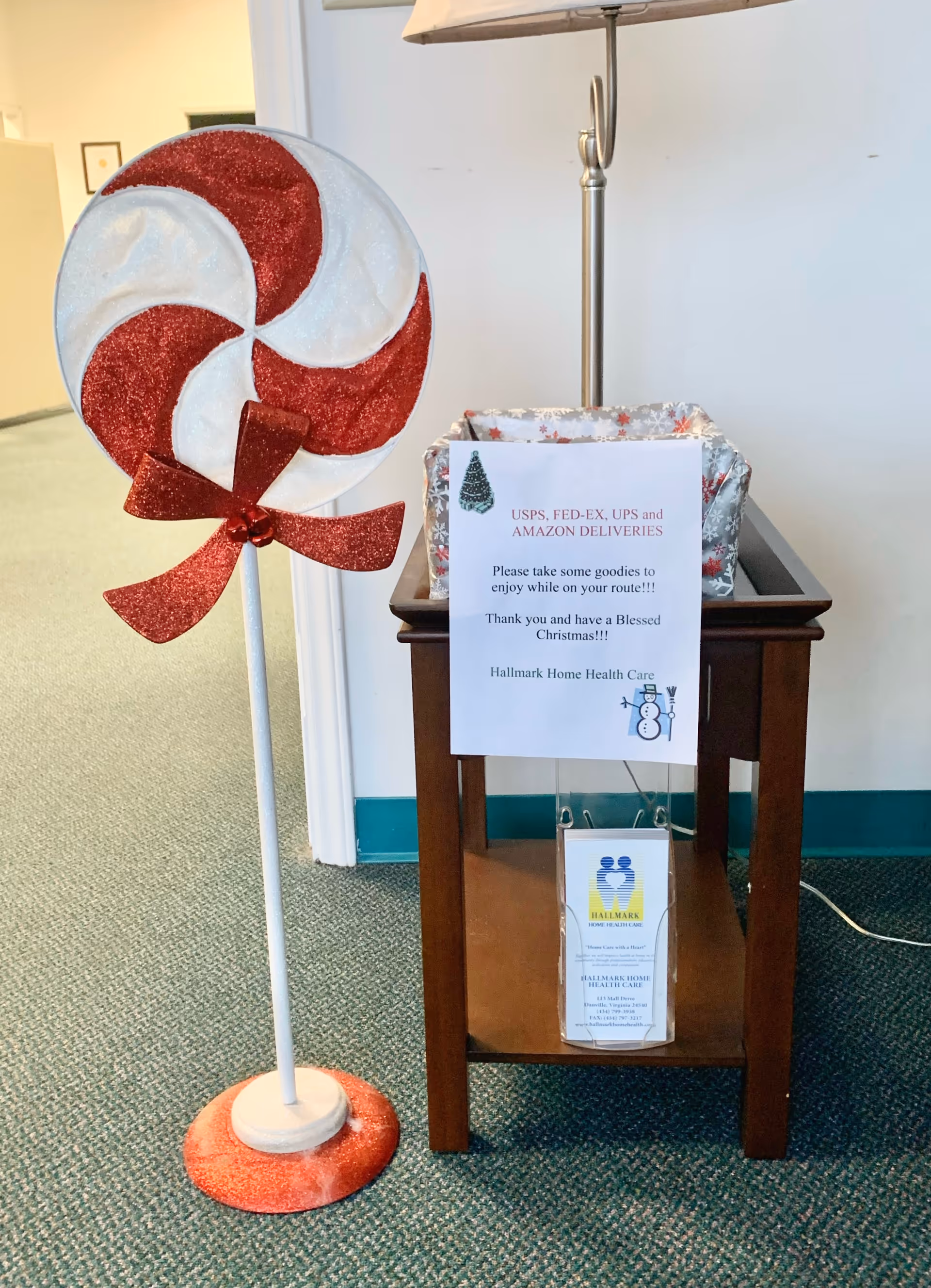 Large red-and-white peppermint prop beside a wooden table with a delivery sign.