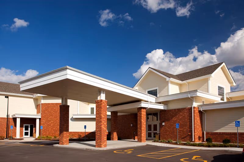 Exterior view of a senior living facility with brick pillars and a covered entrance.