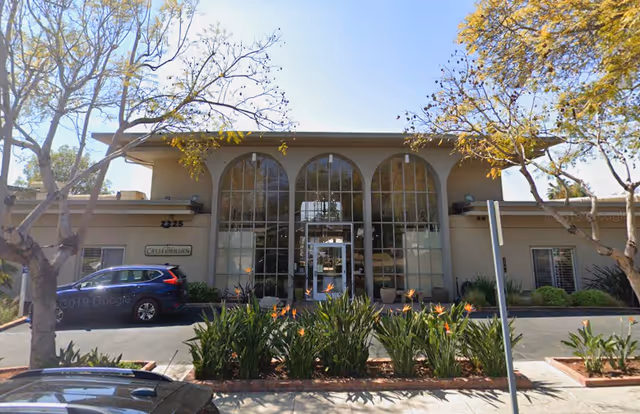 Facade of The Californian senior living facility with large arched windows and landscaped entrance.