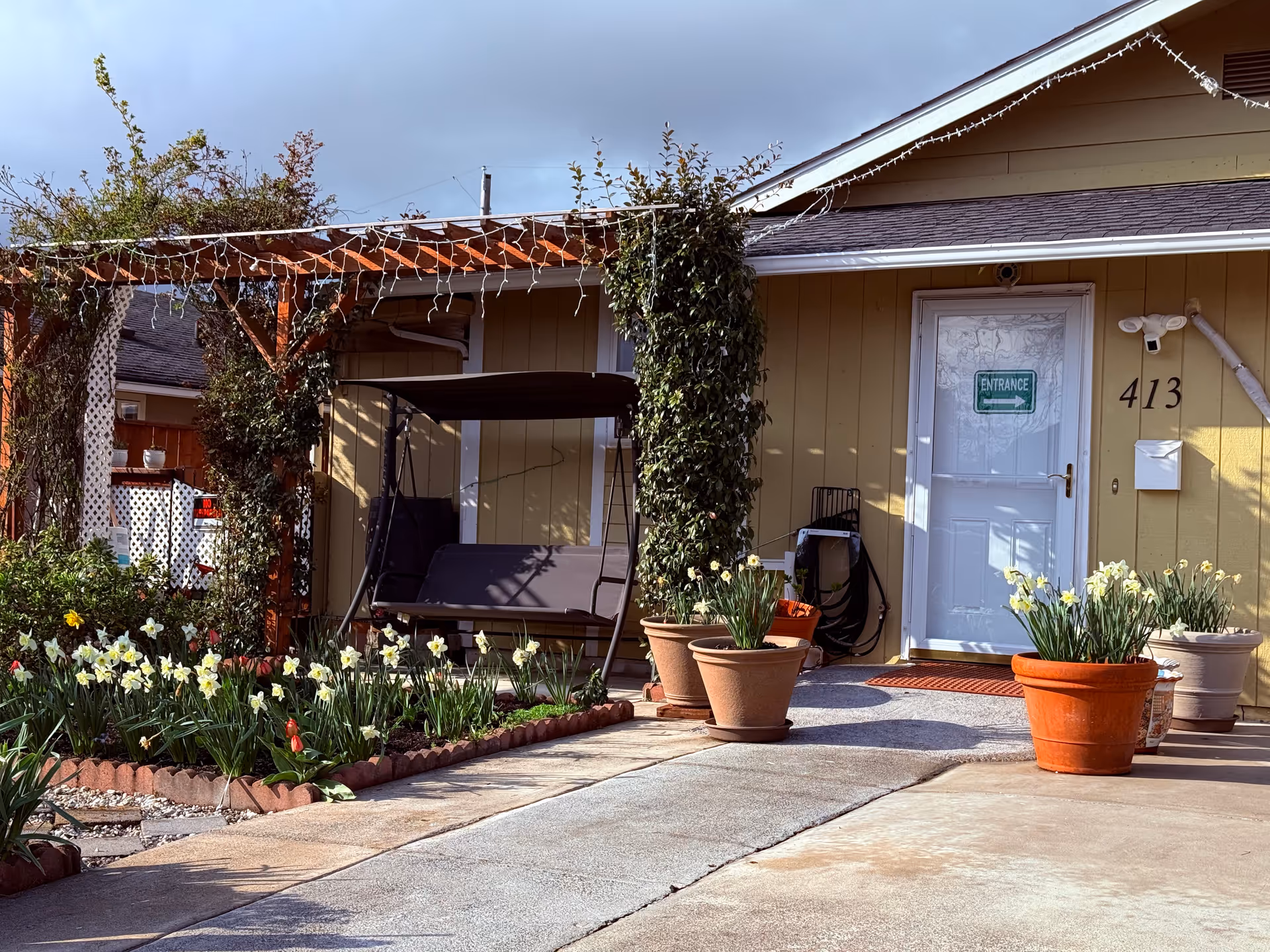 Front exterior of a single-story facility with string lights, planters, and a porch swing.