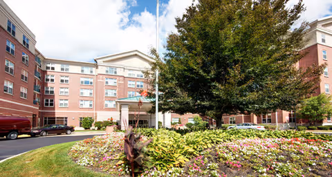 Exterior view of Brookdale Southfield with brick building, trees, and colorful landscaping.