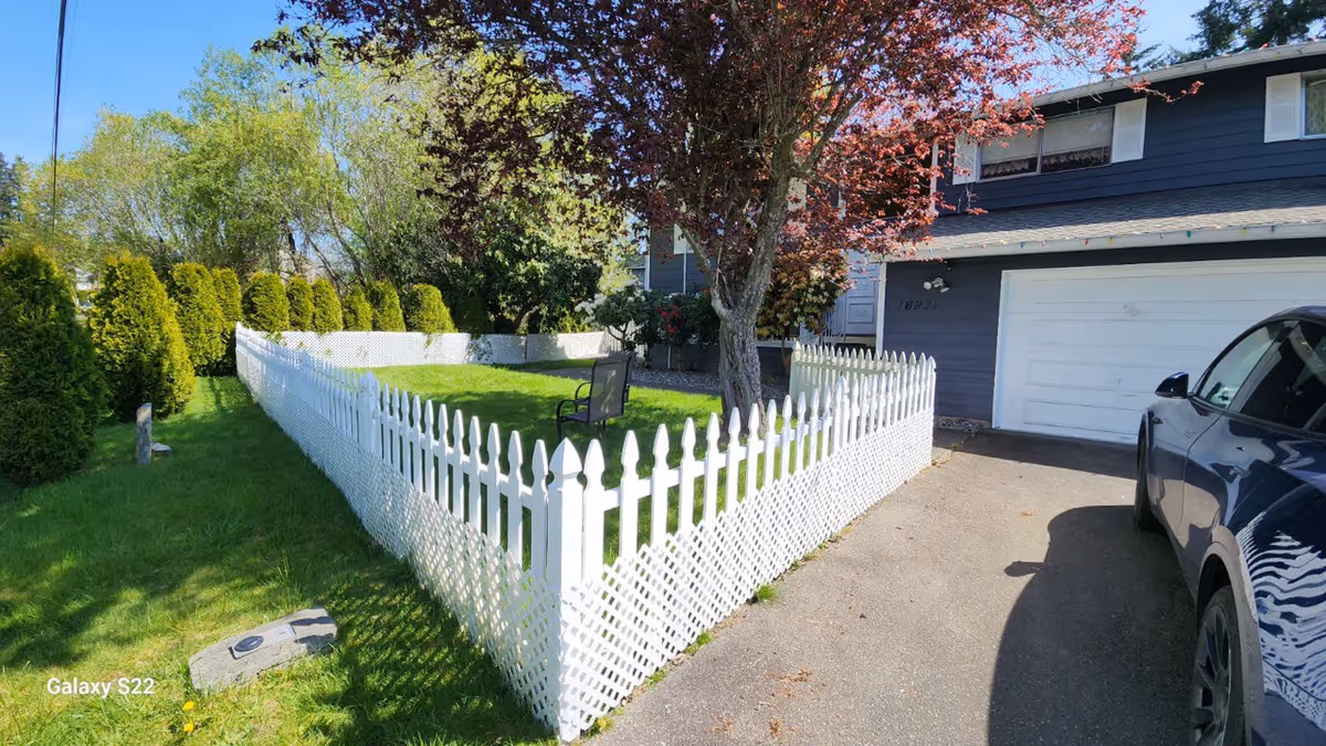 Joy Family Home LLC exterior with a white picket fence, green lawn, and a parked car.