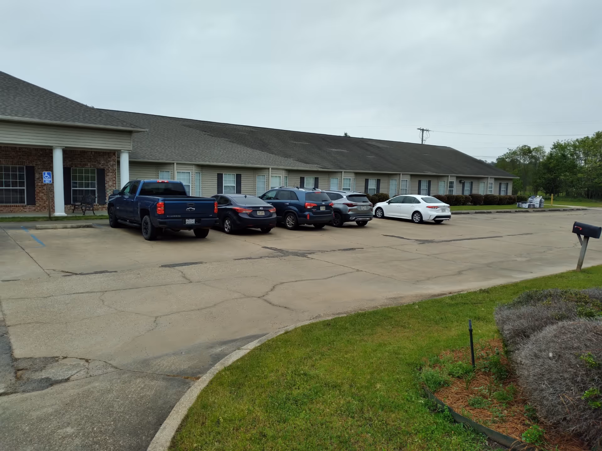Single-story assisted living building with a paved parking lot and surrounding landscaping.