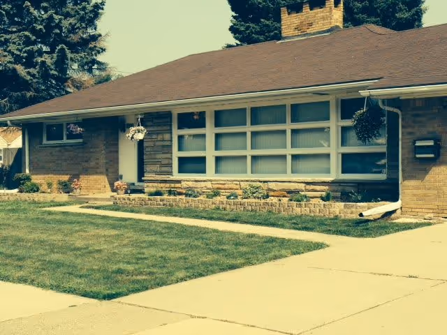 Front exterior of a single-story brick building with large windows, a lawn, and a concrete walkway.