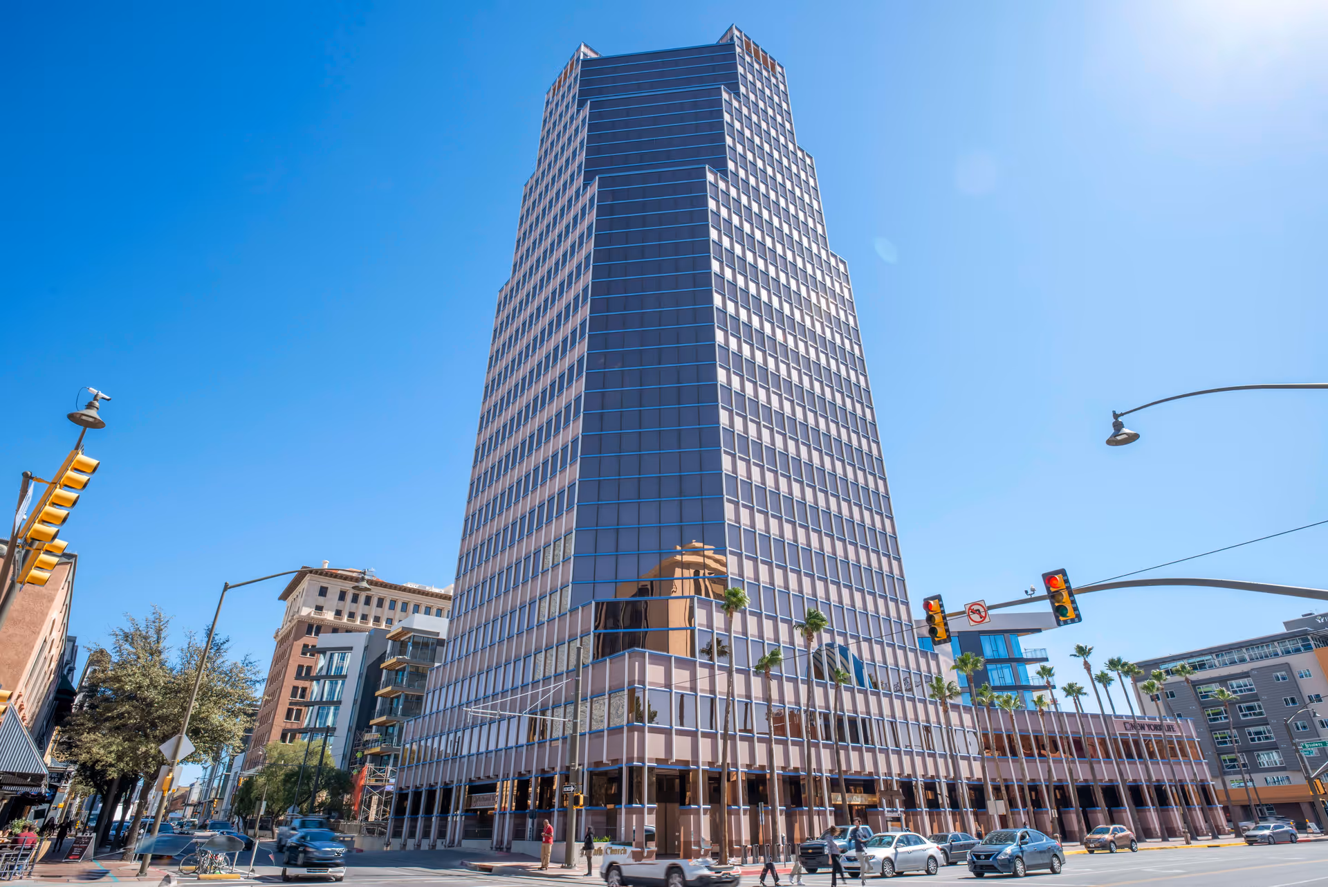 Tall glass office building on a sunny urban street with traffic.
