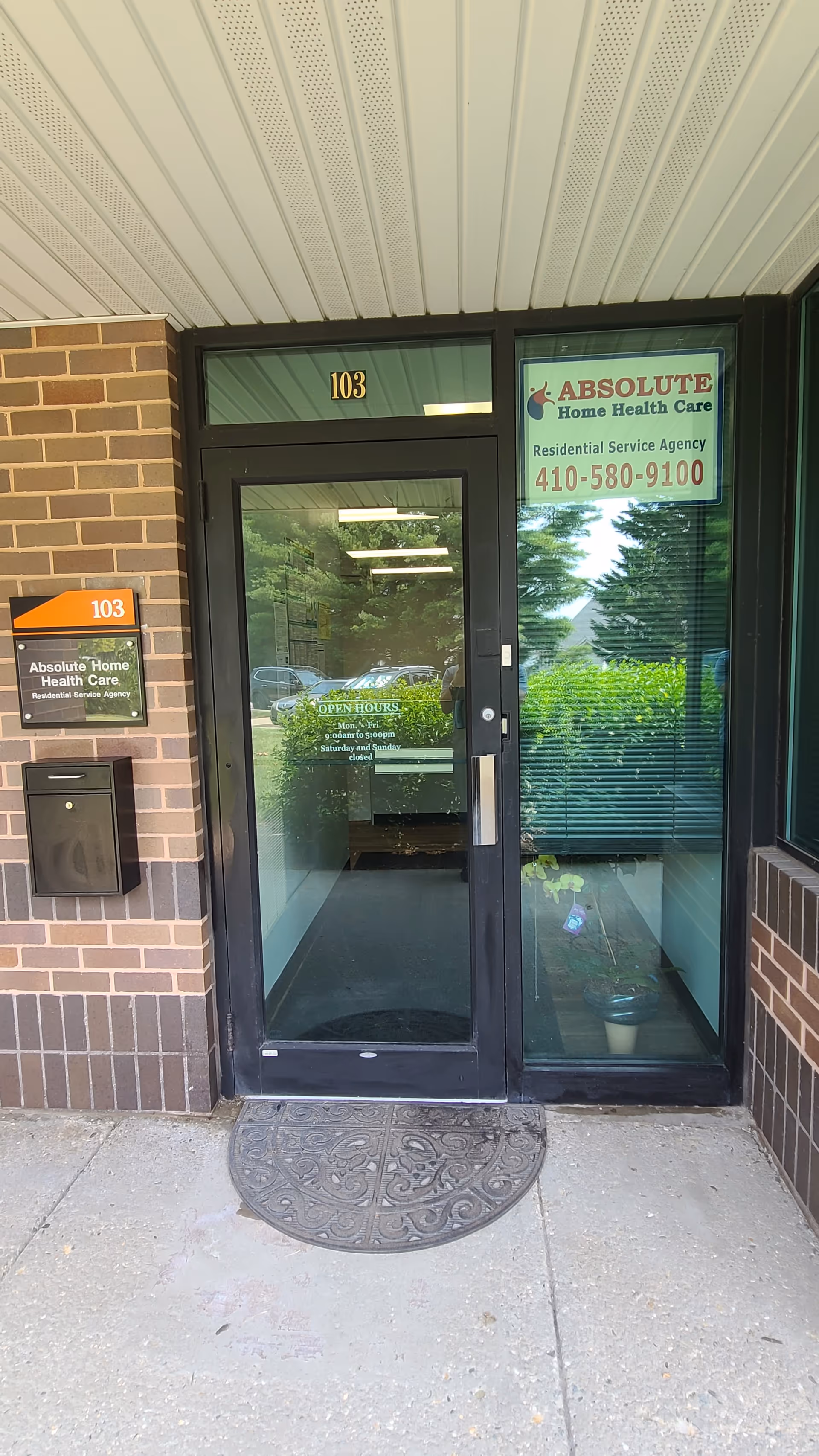 Glass entry door to Absolute Home Health Care with green signage and brick exterior.