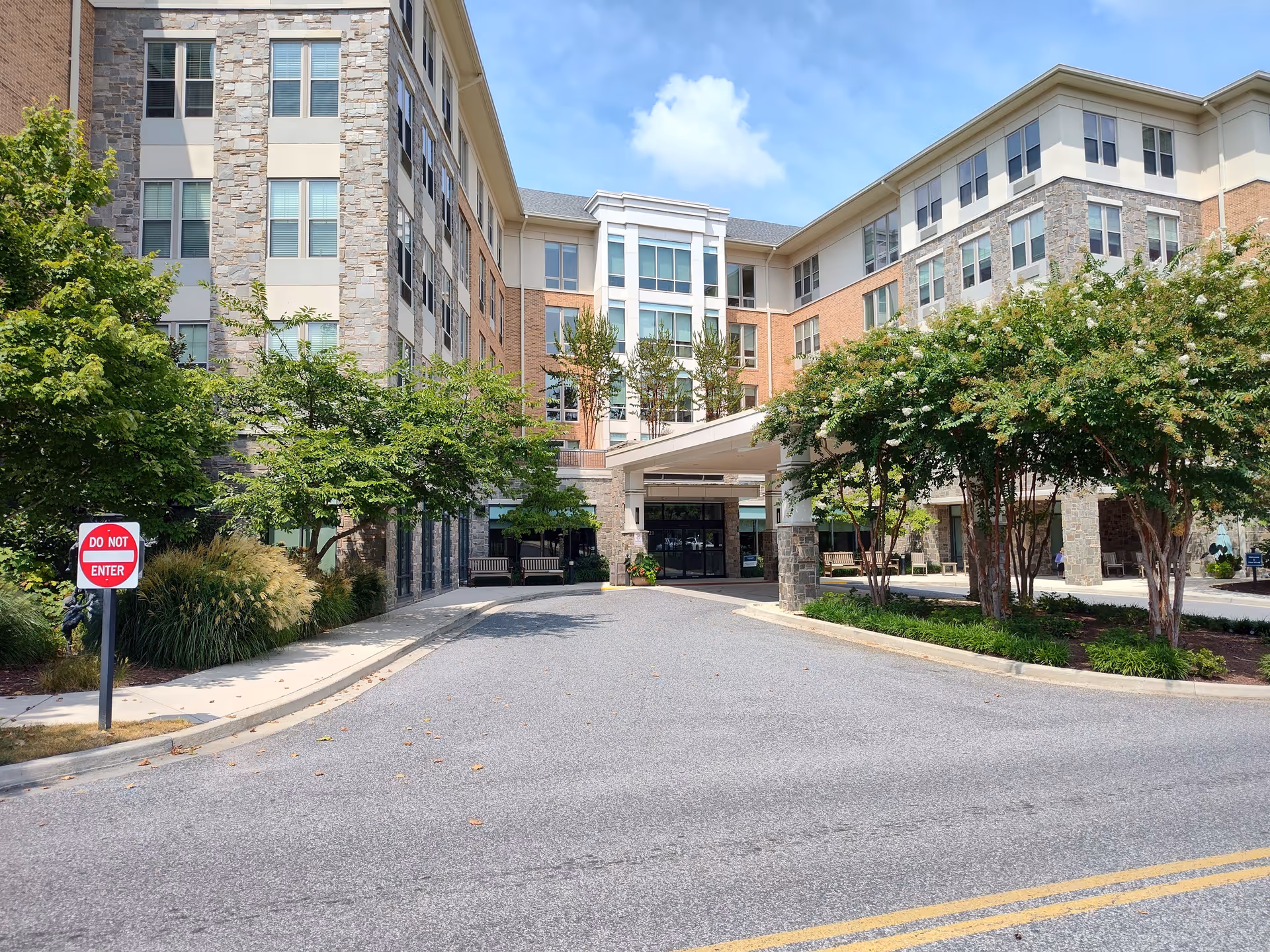 Exterior view of Charlestown Community senior living facility with a driveway, trees, and a covered entrance.