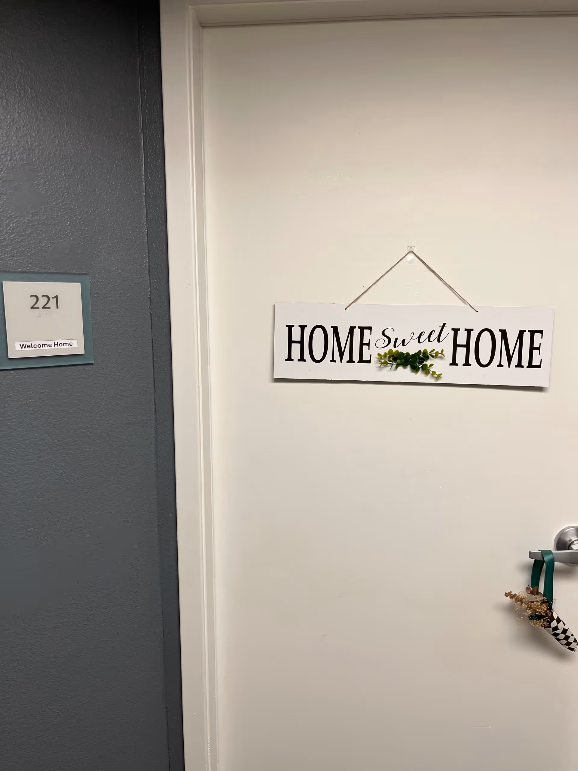 White door with a 'HOME Sweet HOME' sign and a hallway plaque nearby.