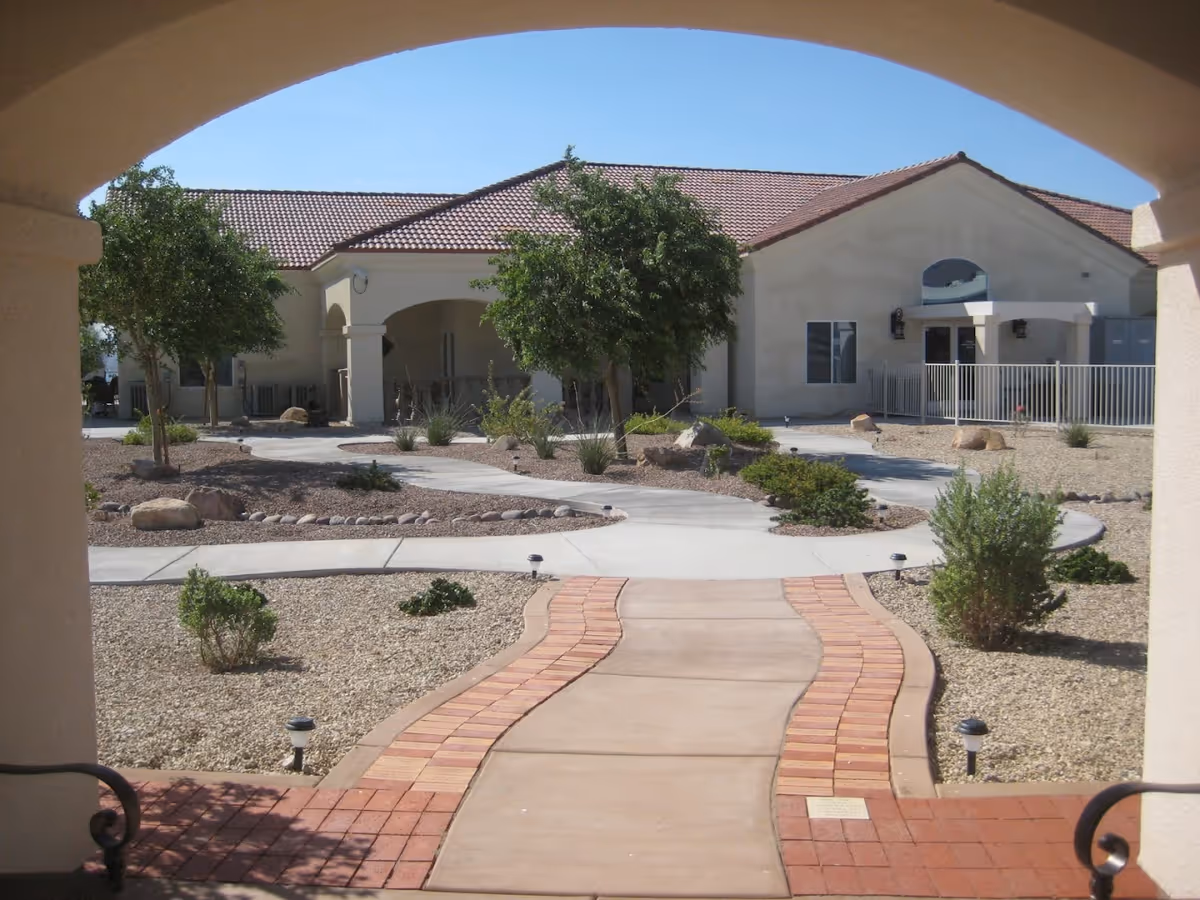 Front view of Lake House Assisted Living exterior with arched entrance and desert landscaping.