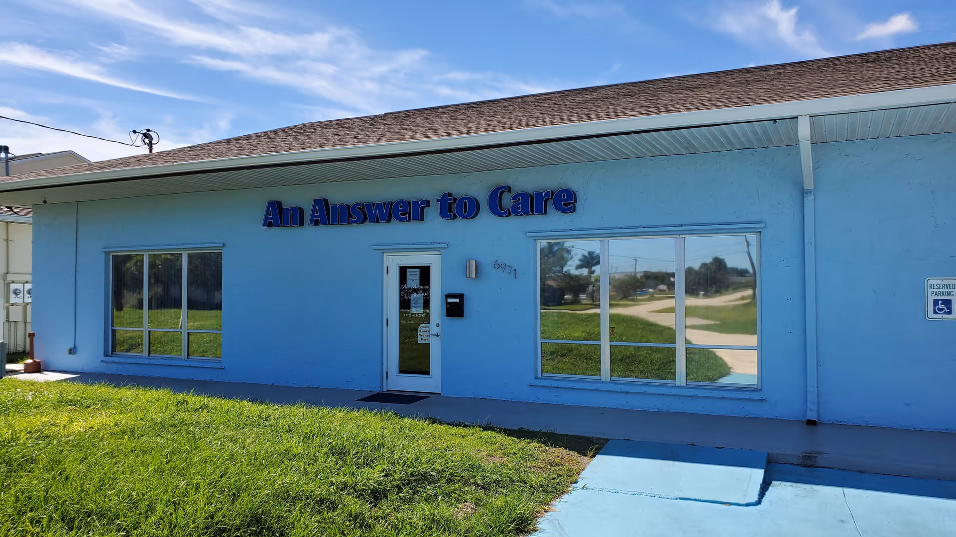 Blue single-story building with An Answer to Care sign and large front windows.