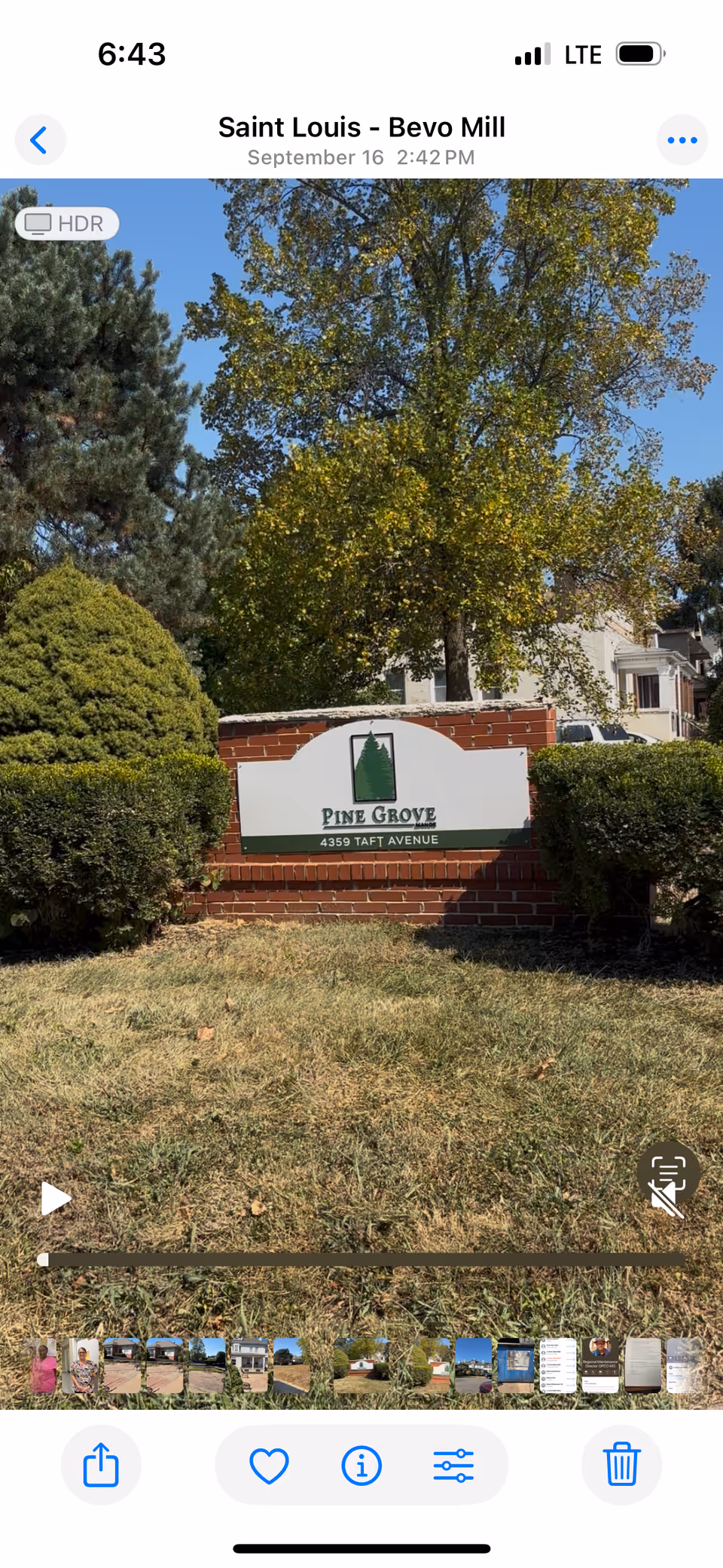 Exterior brick entrance sign for Pine Grove, surrounded by shrubs and trees.
