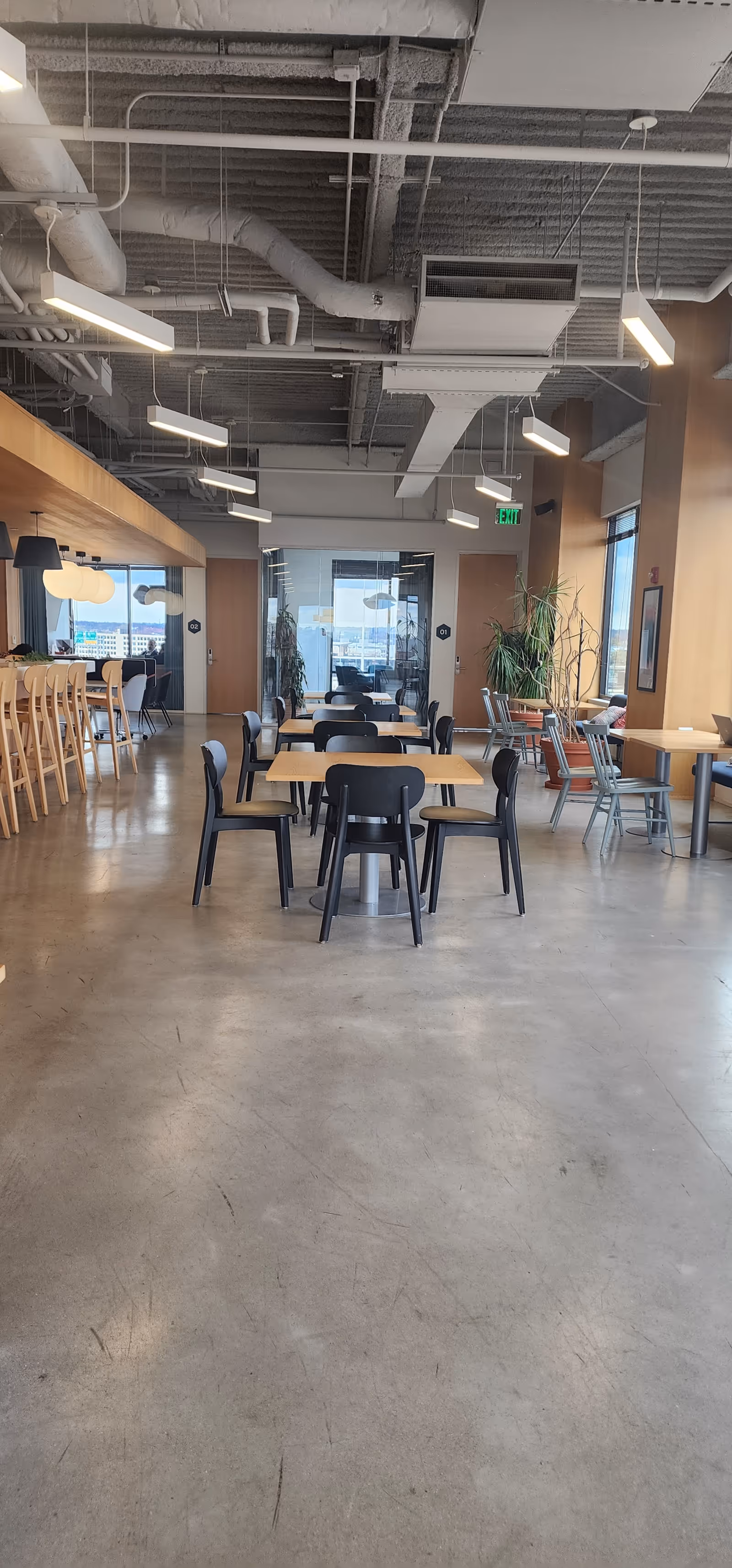 Interior dining area with scattered tables, chairs, and exposed ceilings in a modern facility
